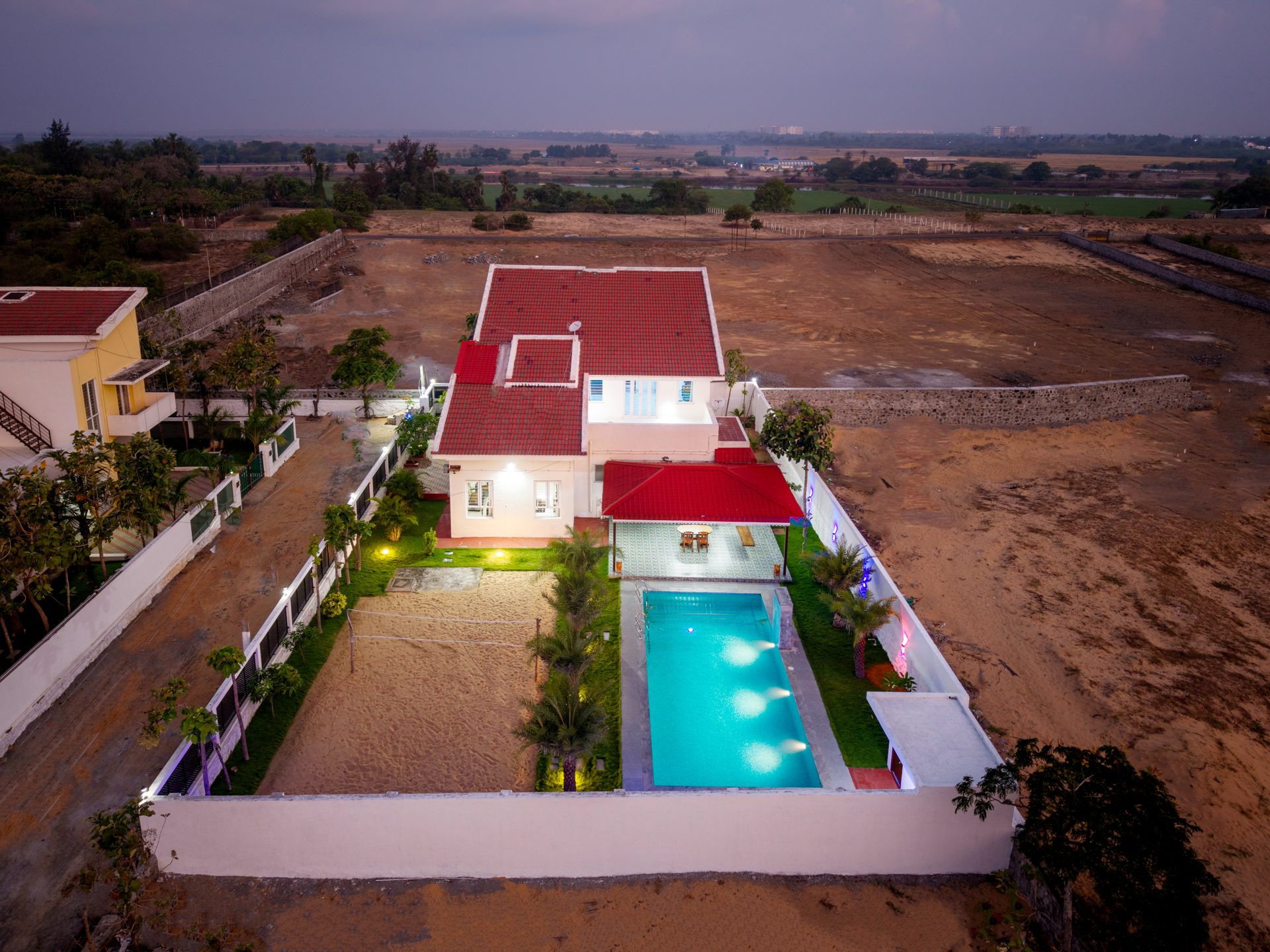 Aerial view of Lotus Villa at dusk with pool and sand court