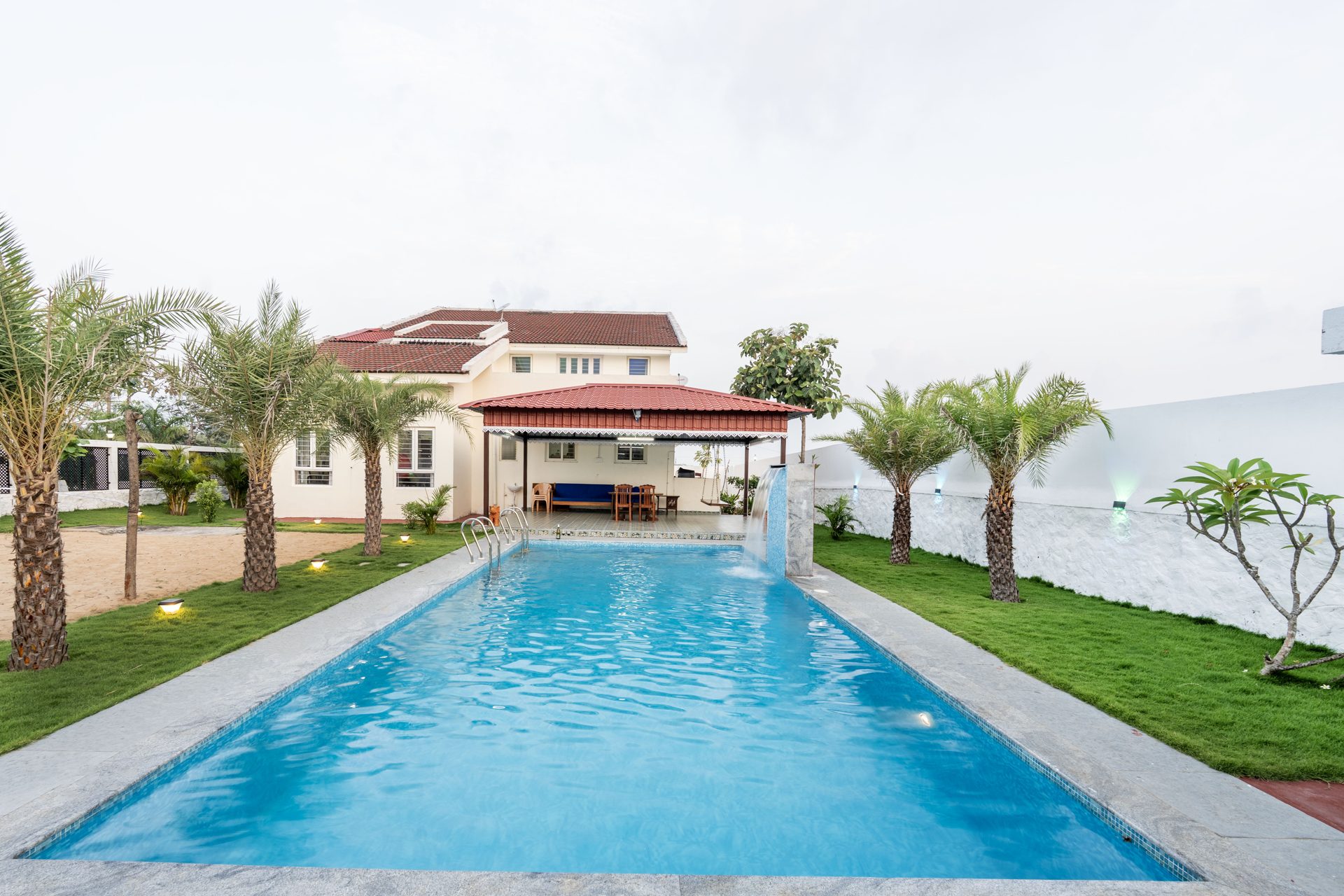 Palm-lined pool with waterfall at Lotus Villa